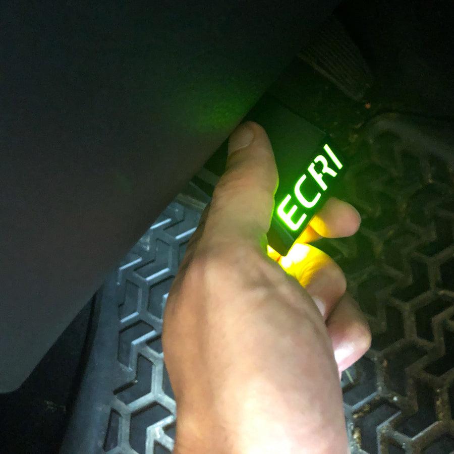 Hand holding a green light with 'ECRI' text against a dark background