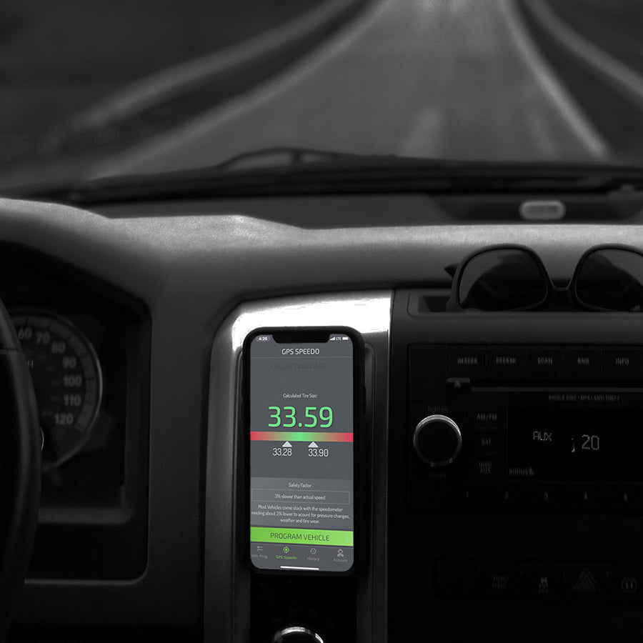 Phone mounted on a car dashboard displaying a speedometer app with a blurred road in the background.